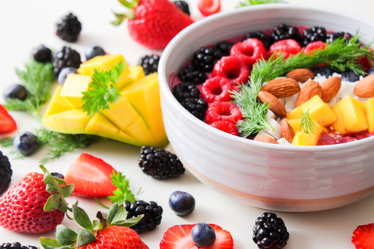 Services A vibrant bowl filled with fresh berries, mango, almonds, and herbs, perfect for a healthy snack or breakfast.