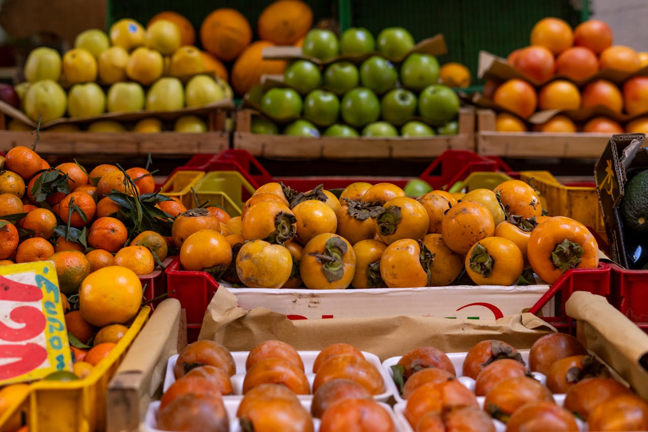 Vibrant fresh fruits like persimmons and tangerines at a market in Rome, Italy.
