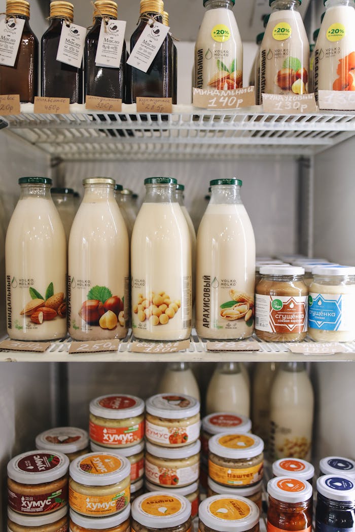 Contact A variety of plant-based milk bottles on display in a refrigerator, showcasing vegan and dairy-free options.